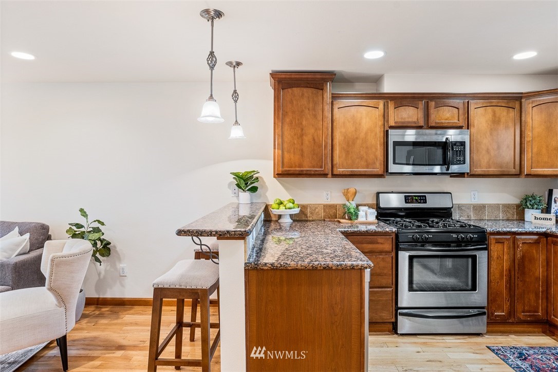 1122 North 92nd Street, Unit B Seattle, WA 98103 - Photo 8 of 32 a kitchen with stainless steel appliances granite countertop a stove a sink and a microwave