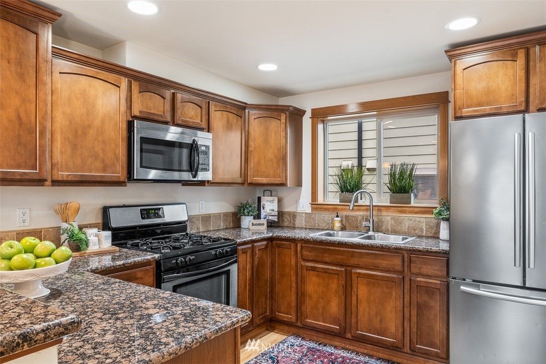 1122 North 92nd Street, Unit B Seattle, WA 98103 - Photo 10 of 32 a kitchen with stainless steel appliances granite countertop a refrigerator sink and stove