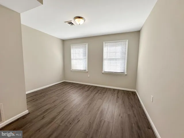 a view of an empty room with wooden floor and window