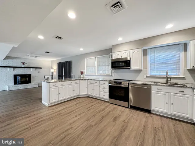 a kitchen with stainless steel appliances kitchen island granite countertop a table chairs sink and cabinets