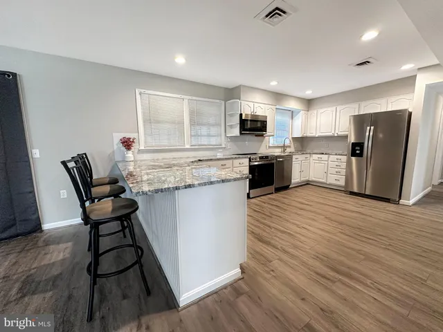 a living room with stainless steel appliances furniture and a kitchen view