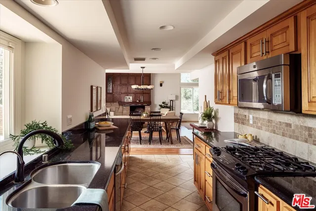 a kitchen with kitchen island granite countertop a stove a sink a dining table and chairs