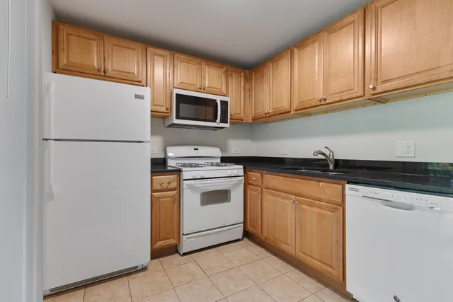 a kitchen with stainless steel appliances granite countertop a refrigerator stove a sink and dishwasher with wooden cabinets