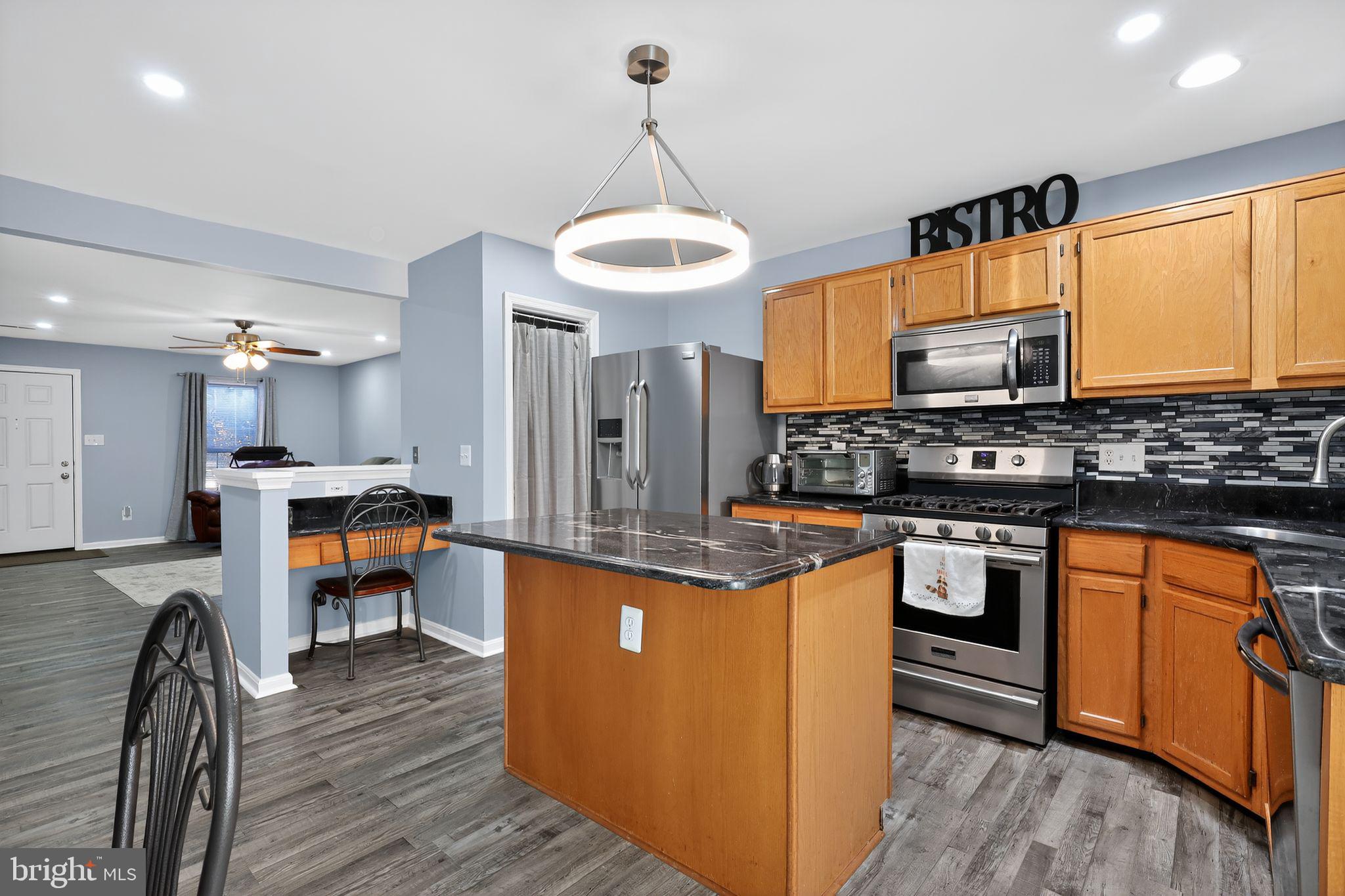 45481 Bluemont Junction Square Sterling, VA 20164 - Photo 6 of 30 a kitchen with stainless steel appliances kitchen island granite countertop a stove a sink and a refrigerator