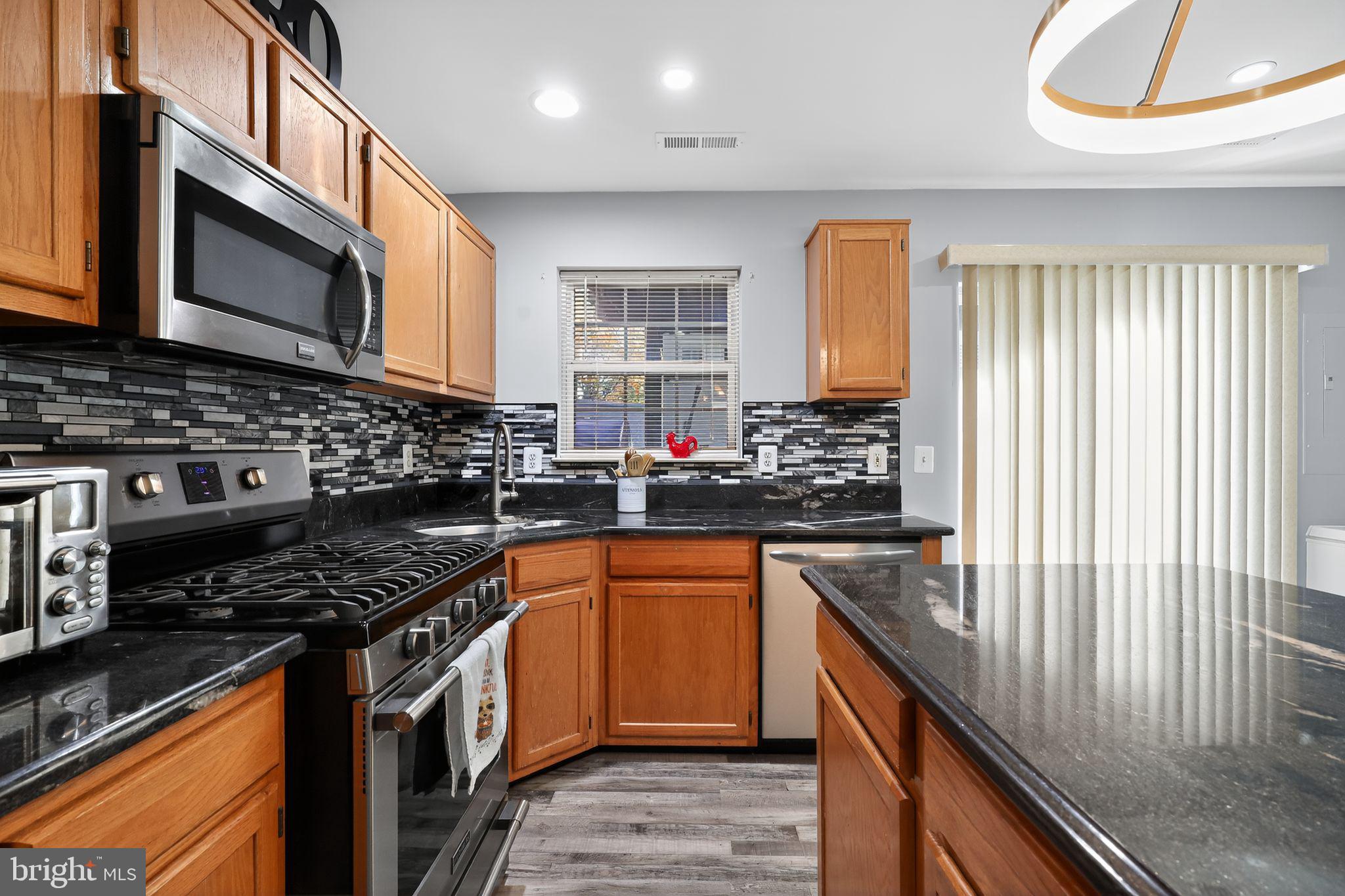 45481 Bluemont Junction Square Sterling, VA 20164 - Photo 7 of 30 a kitchen with stainless steel appliances granite countertop a stove a sink and a microwave