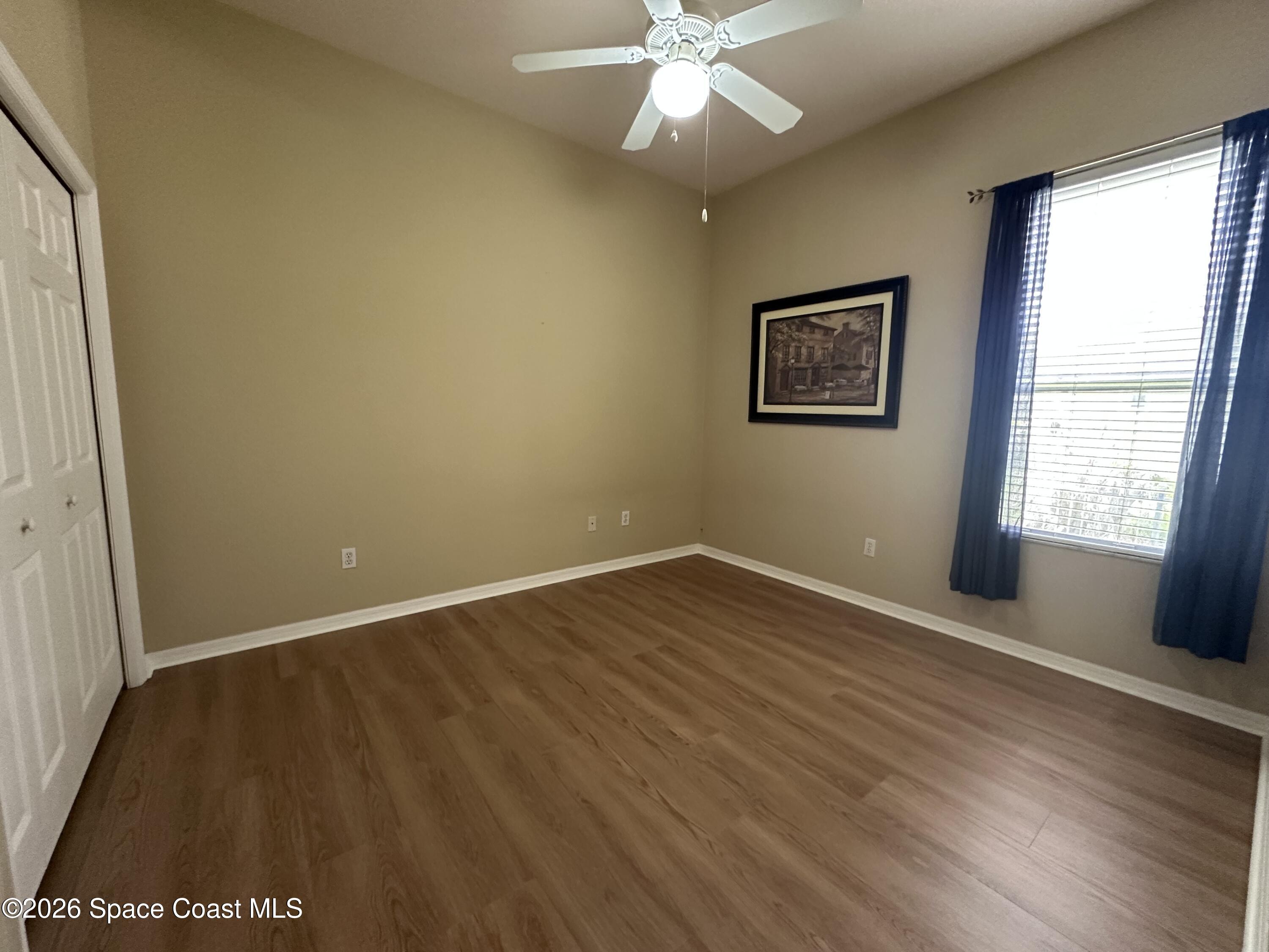 883 Spring Oak Drive Melbourne, FL 32901 - Photo 31 of 45 an empty room with wooden floor fan and windows