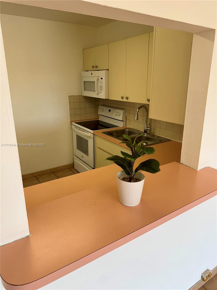 1075 West 68th Street, Unit 314 Hialeah, FL 33014 - Photo 3 of 27 a kitchen with a sink and a stove top oven