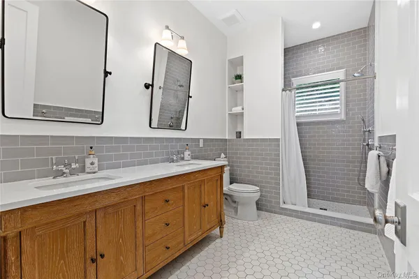 a bathroom with a double vanity sink a toilet and a mirror