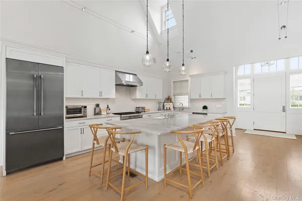 a kitchen with stainless steel appliances granite countertop a sink a stove a refrigerator and island with wooden floor