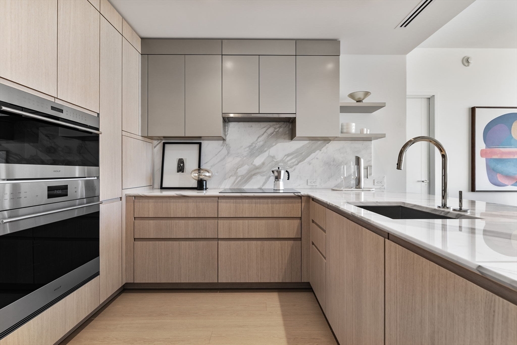 682 Atlantic Avenue, Unit 37D Boston, MA 02111 - Photo 7 of 42 a kitchen with kitchen island granite countertop a sink stainless steel appliances and cabinets