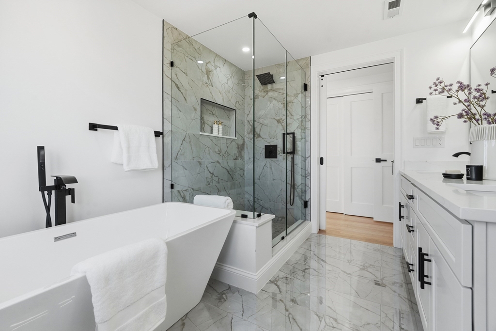 171 Shaw Road Brookline, MA 02467 - Photo 27 of 42 a bathroom with a double vanity sink a large mirror and shower