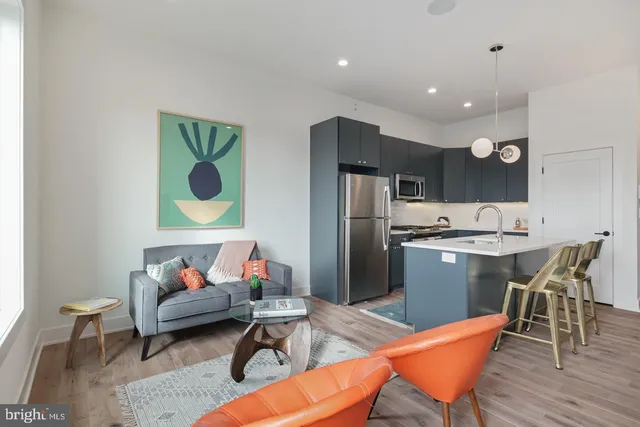 a living room with stainless steel appliances furniture dining table and wooden floor