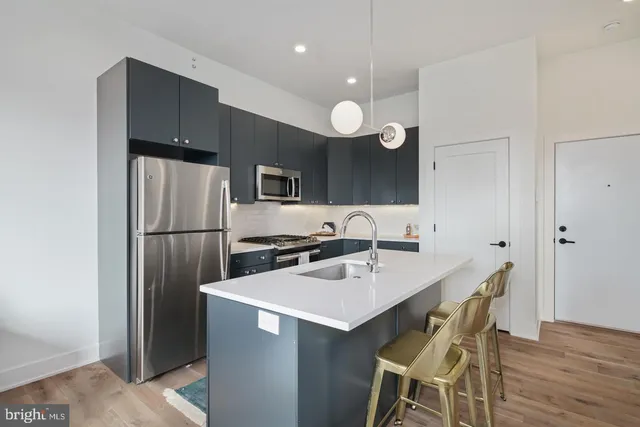 a kitchen with a sink a refrigerator and chairs