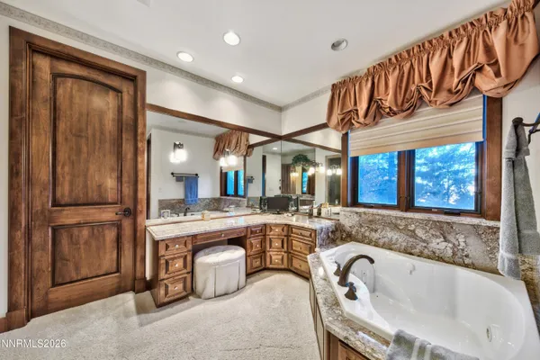 a spacious bathroom with a granite countertop double vanity sink a mirror and a bathtub