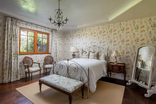 a bedroom with a bed a couch and dresser with wooden floor