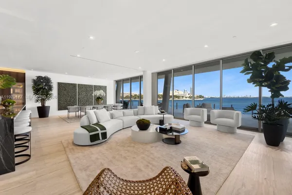 a living room with furniture potted plant and kitchen view