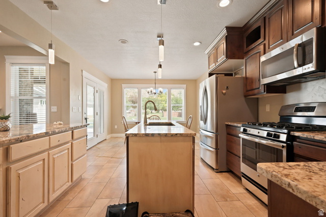 580 North 300 East Logan, UT 84321 - Photo 33 of 74 Spacious kitchen featuring an island with an undermount sink and gooseneck faucet, light-toned cabinetry, stainless steel appliances, and tile flooring
