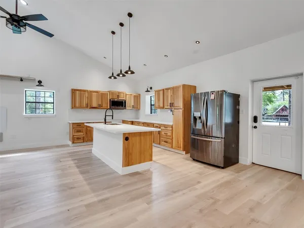 a kitchen with stainless steel appliances kitchen island a refrigerator sink and cabinets