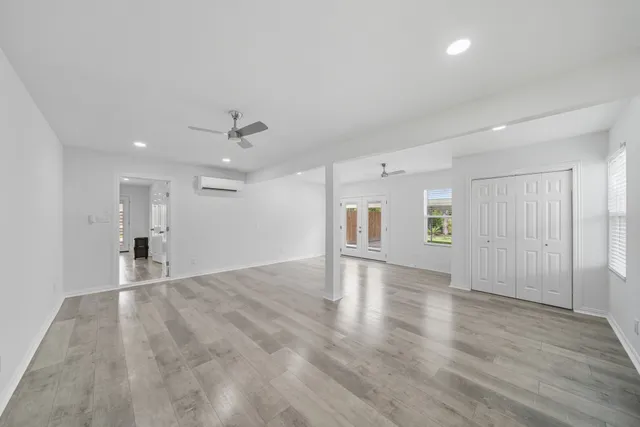 a view of an empty room with window and wooden floor