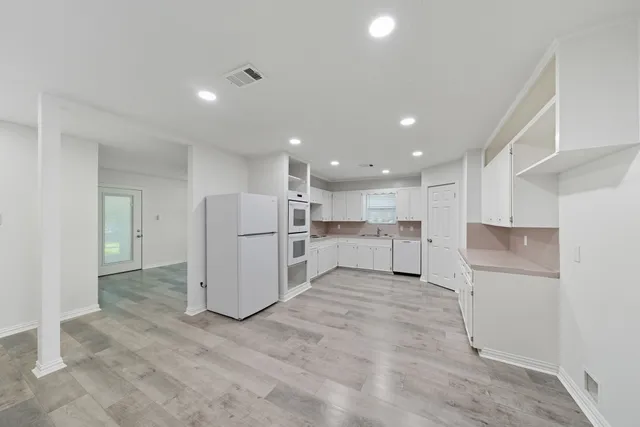a view of a kitchen with refrigerator and white cabinets