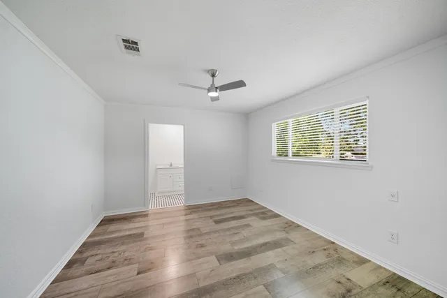 an empty room with a ceiling fan and windows