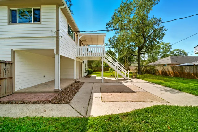 a view of a white house with a small yard and a large tree