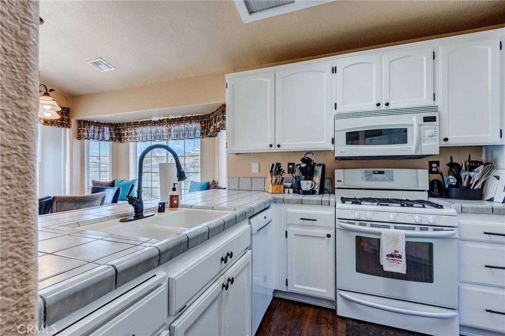 7170 Joshua Road Oak Hills, CA 92344 - Photo 25 of 58 a kitchen with white cabinets and appliances