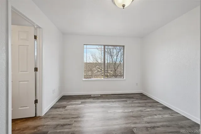 an empty room with wooden floor and window