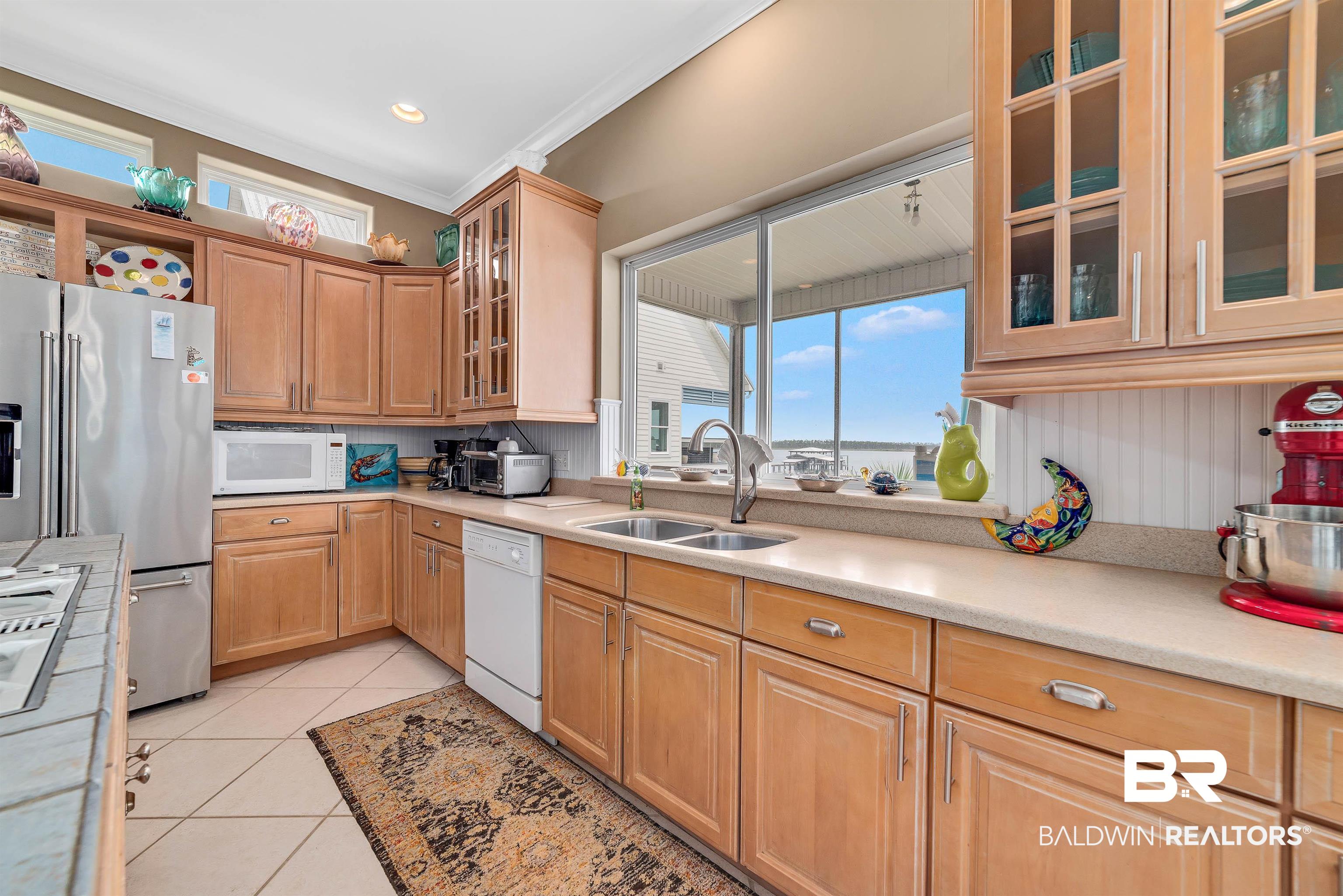 24513 Gulf Bay Road Orange Beach, AL 36561 - Photo 14 of 52 Kitchen with light tile patterned floors, crown molding, white appliances, and sink