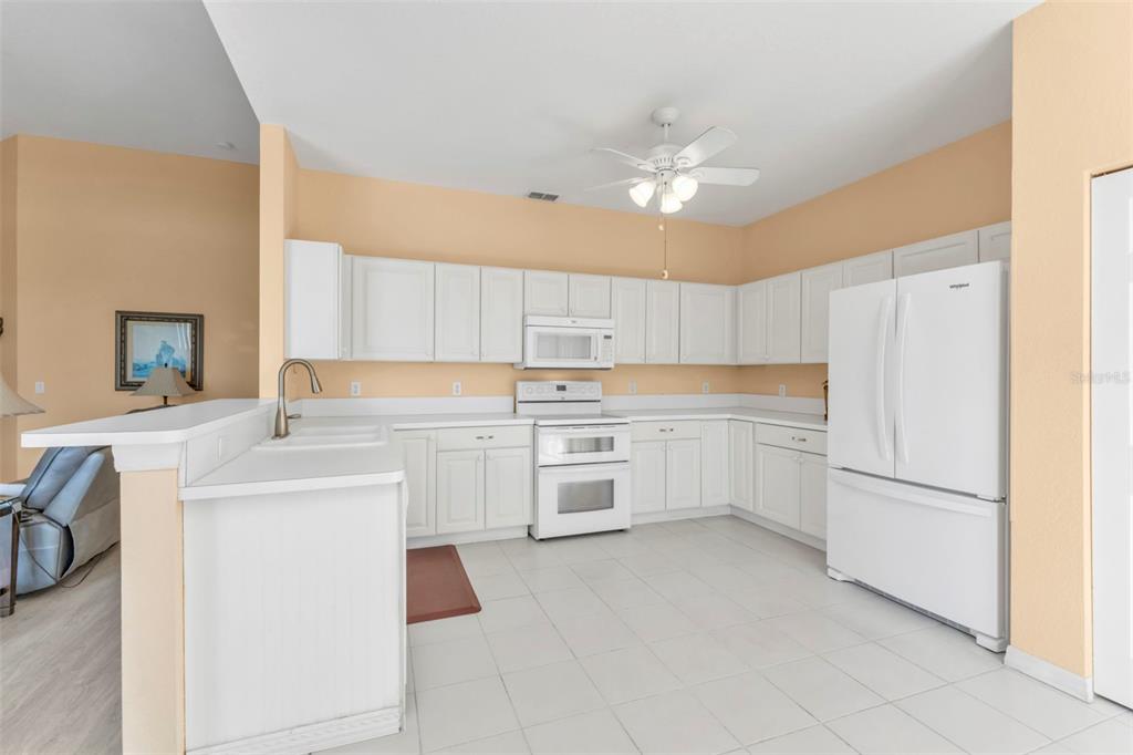 24088 Buckingham Way Punta Gorda, FL 33980 - Photo 7 of 37 a kitchen with white cabinets and white appliances