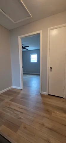 a view of an empty room with wooden floor and a window