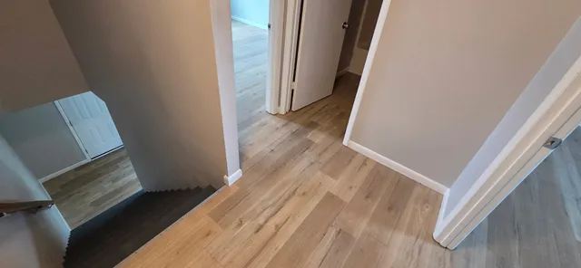 a view of a hallway with wooden floor and staircase