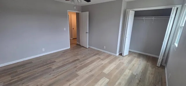 a view of an empty room with wooden floor and a window