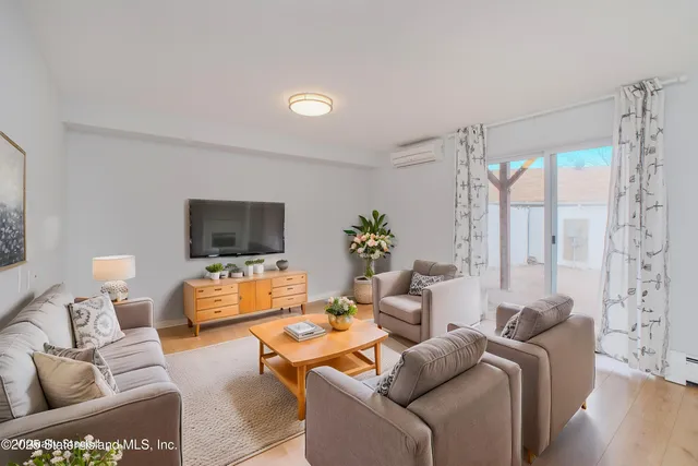 a living room with furniture a flat screen tv and a large window