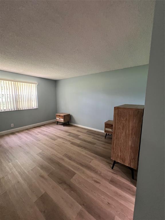1605 Abaco Drive, Unit 1605 J1 Coconut Creek, FL 33066 - Photo 29 of 71 a hallway with a chair and wooden floor