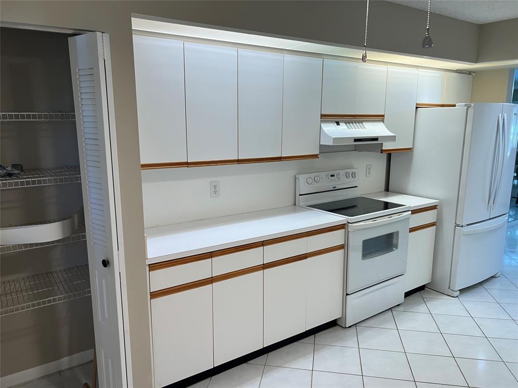 1605 Abaco Drive, Unit 1605 J1 Coconut Creek, FL 33066 - Photo 59 of 71 a kitchen with white cabinets and white appliances
