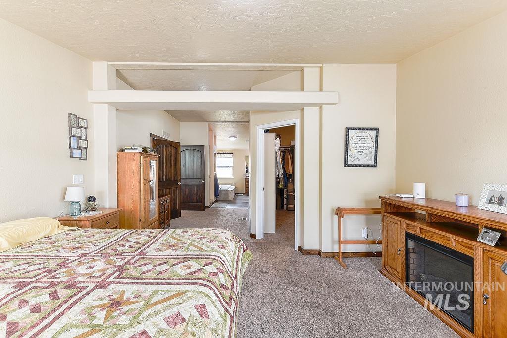 414 South Garfield Street Genesee, ID 83832 - Photo 23 of 50 Bedroom with a walk in closet, light carpet, a glass covered fireplace, and a textured ceiling