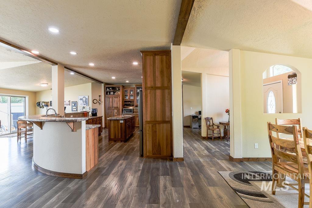 414 South Garfield Street Genesee, ID 83832 - Photo 7 of 50 Kitchen featuring a textured ceiling, a breakfast bar area, dark wood-style flooring, dark stone counters, and beam ceiling