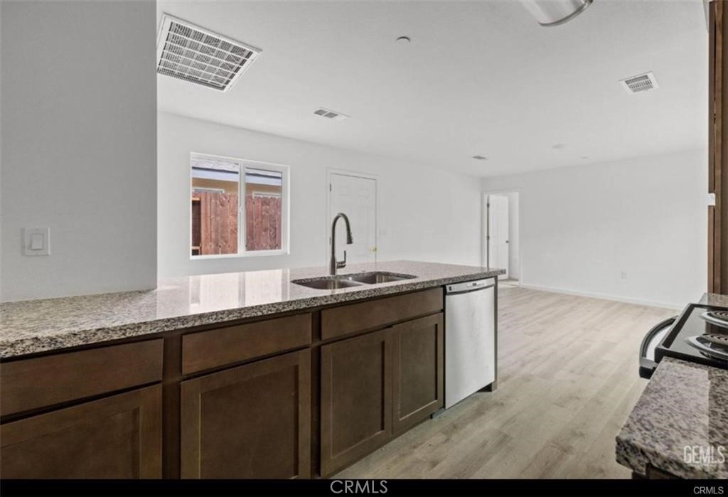 1413 Oregon Street Bakersfield, CA 93305 - Photo 5 of 8 a kitchen with granite countertop a sink and a stove with wooden floor