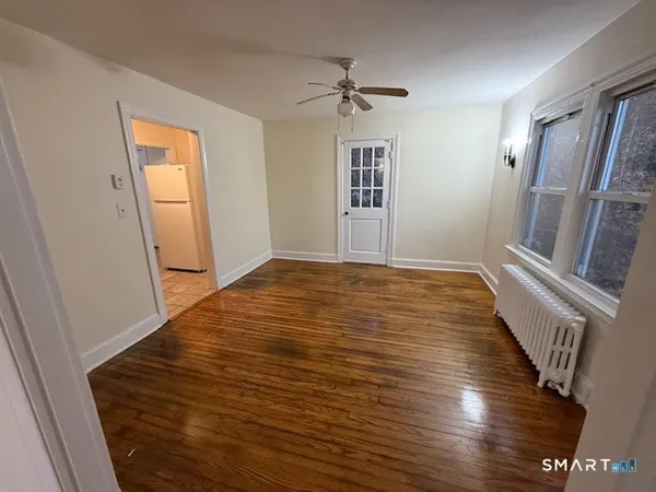 a view of an empty room with wooden floor and a window