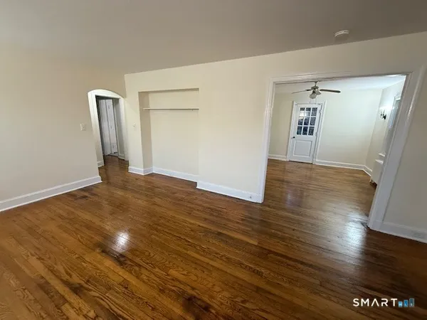 a view of an empty room with wooden floor and a window