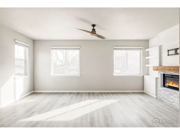 a view of an empty room with window and wooden floor