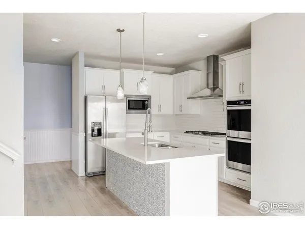 a kitchen with kitchen island a sink stainless steel appliances white cabinets and wooden floor