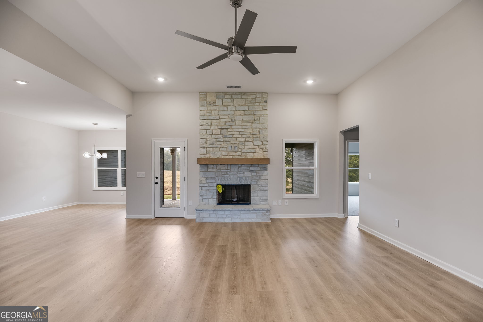 3356 Veal Road Roopville, GA 30170 - Photo 7 of 45 an empty room with wooden floor a fireplace and windows