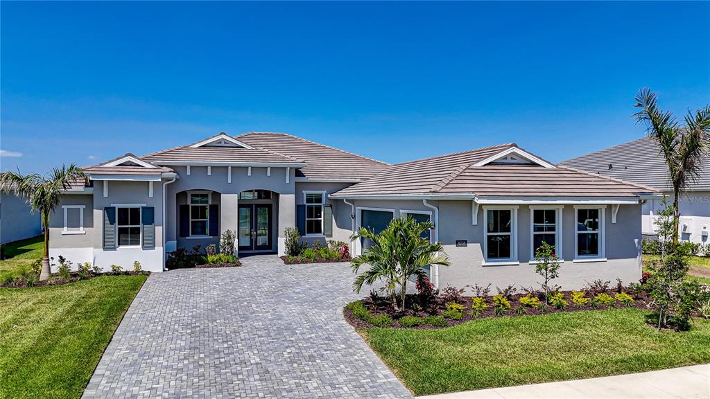 8218 Nevis Run Lakewood Ranch, FL 34202 - Photo 1 of 48 a front view of a house with a yard potted plants and a table