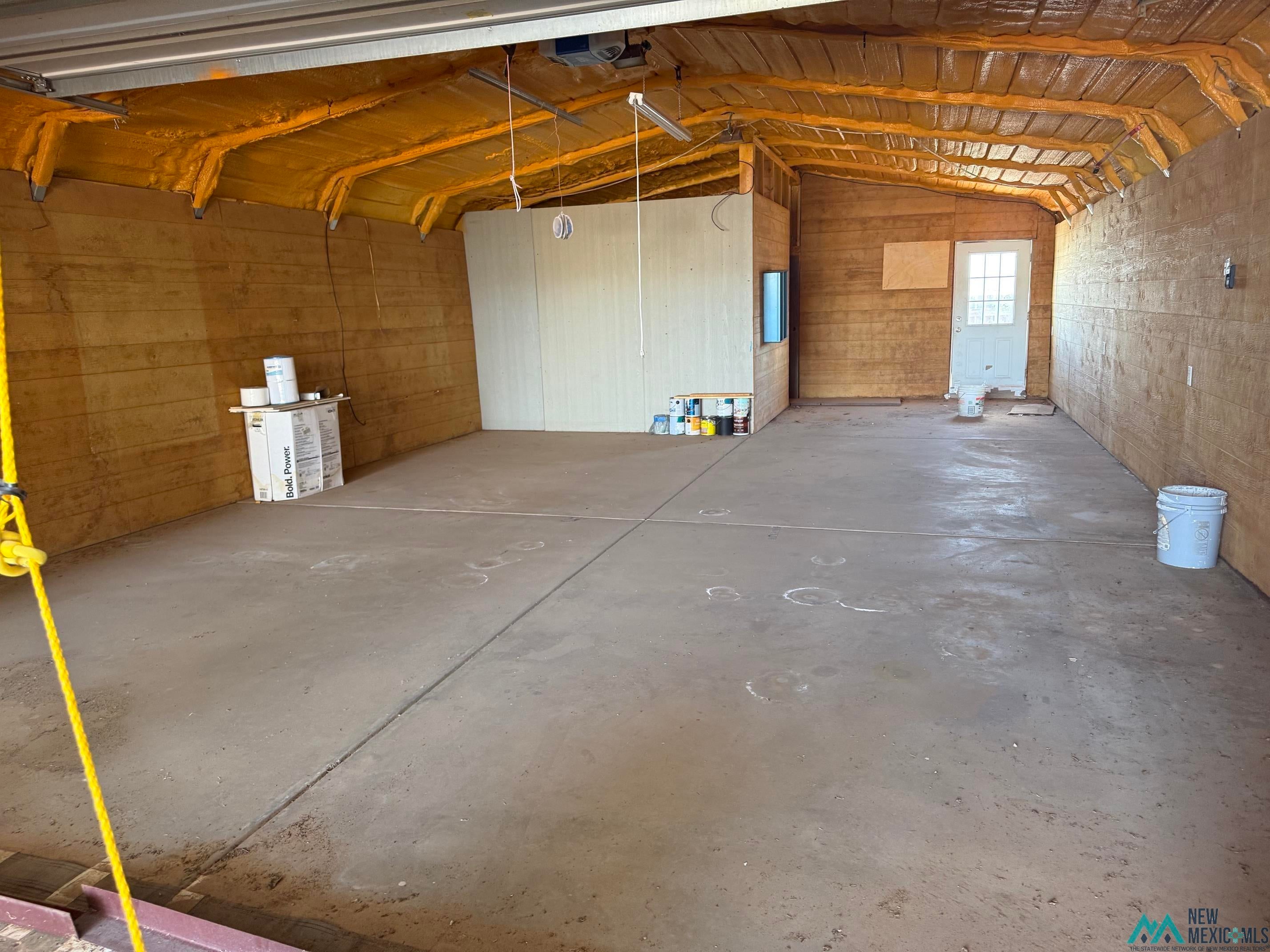 104 Shawnee Road Logan, NM 88426 - Photo 34 of 36 Concrete flooring with visible expansion joints, complemented by spray foam insulation on the ceiling and upper walls, and wood paneling on the lower walls