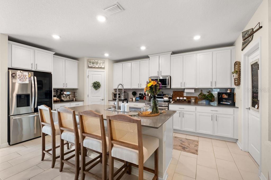 2821 Muller Oak Loop Ocoee, FL 34761 - Photo 14 of 45 a kitchen with stainless steel appliances granite countertop a refrigerator a stove a sink a table and chairs
