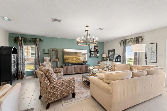 a living room with furniture a flat screen tv and a chandelier