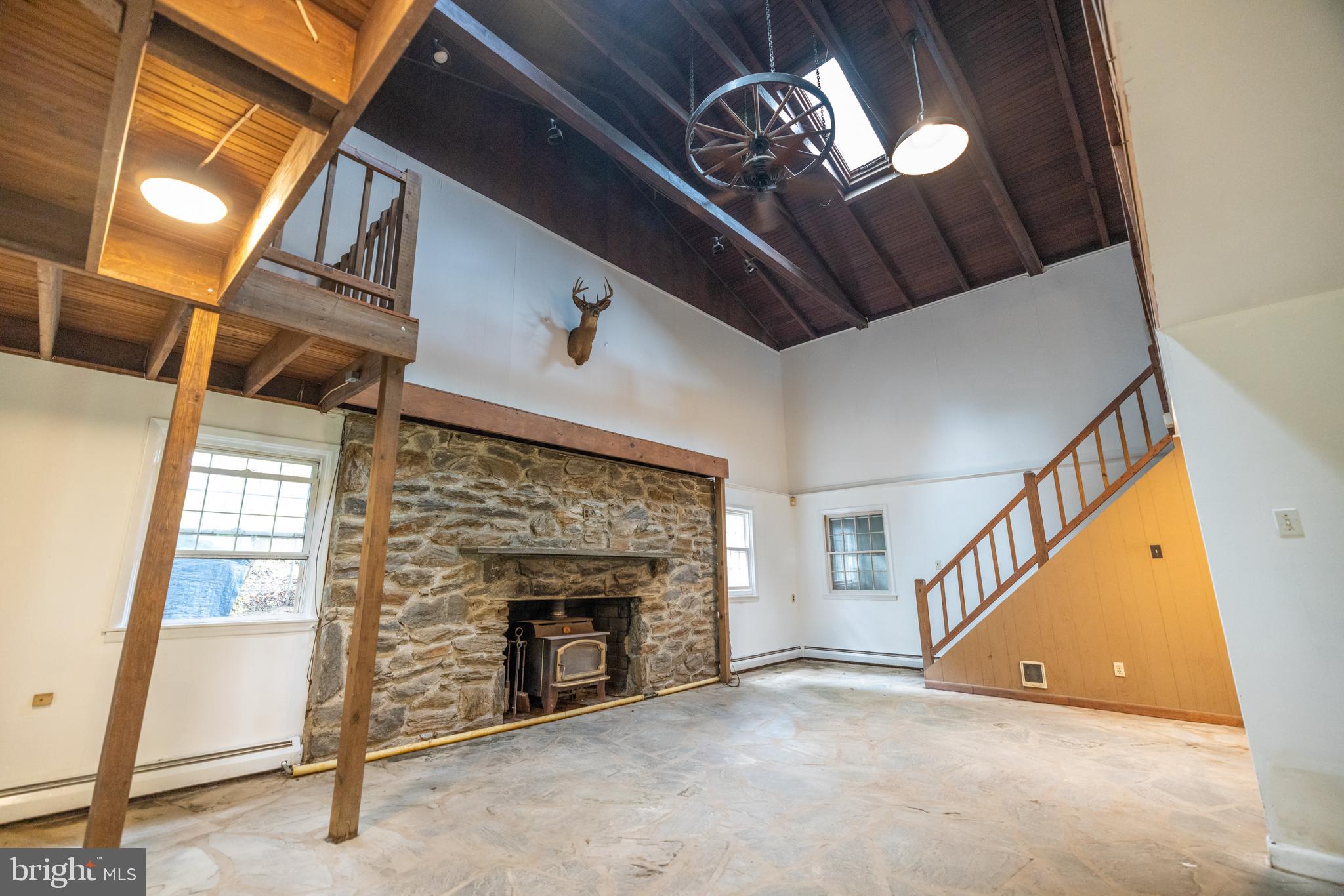 160 Stoney Bank Road Glen Mills, PA 19342 - Photo 14 of 46 a view of a livingroom with an empty space a fireplace wooden floor and windows