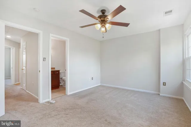 an empty room with chandelier fan and windows